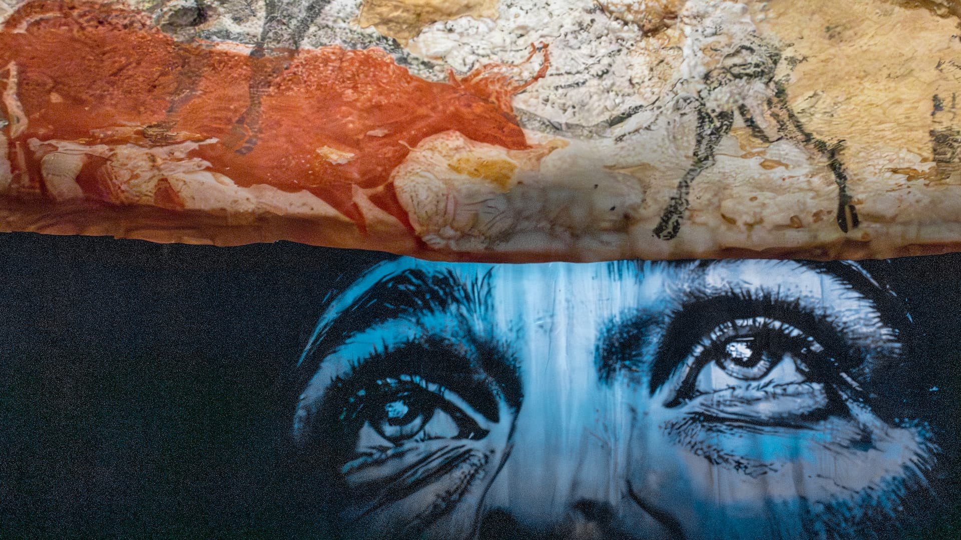 The facsimile’s painted wall and, projected just below it, a face whose gaze rises towards the animals