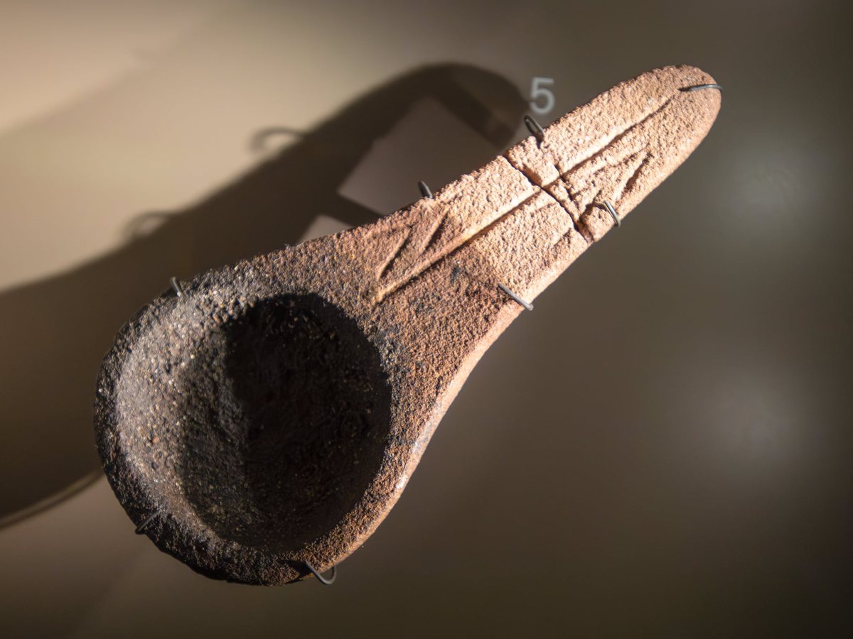 Objet en pierre à cupule et gravures, présenté sur fond sombre