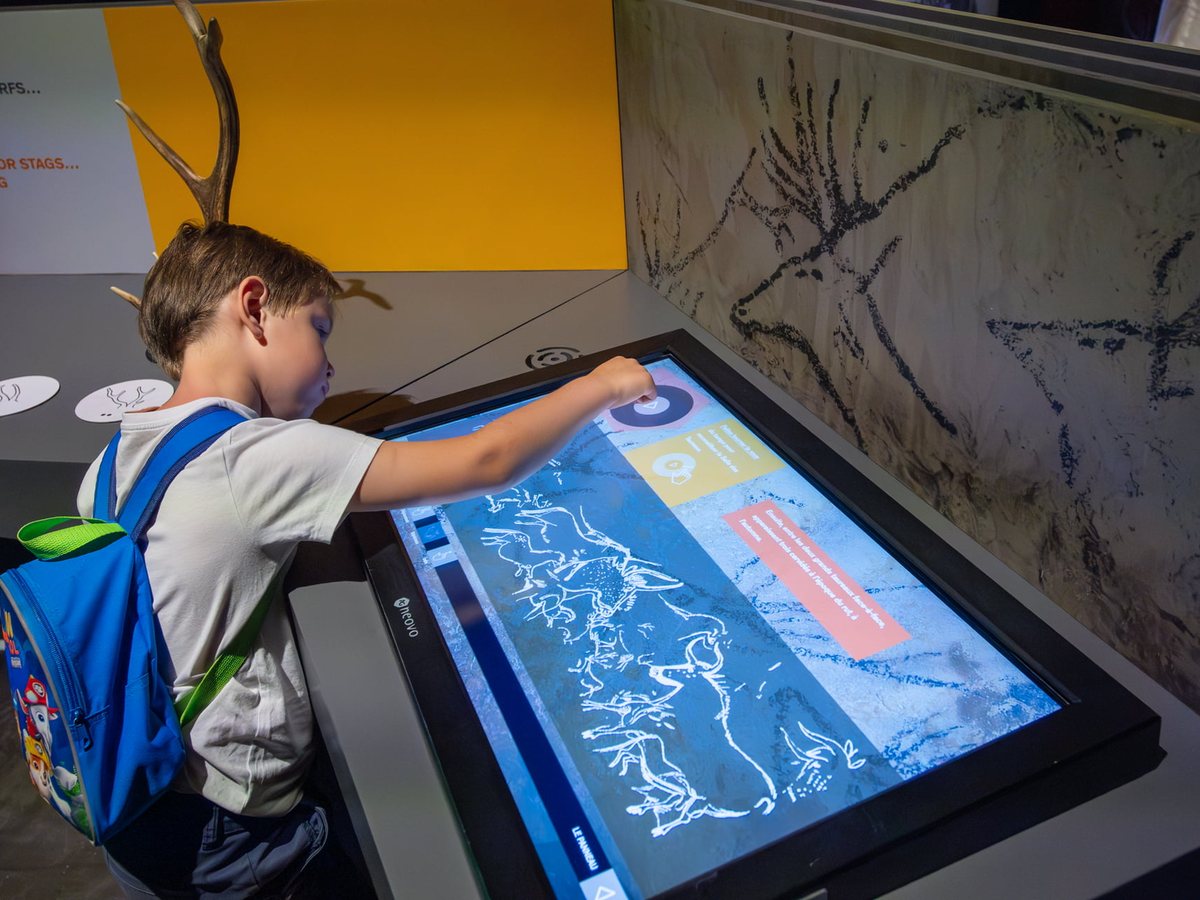 A child using a touch table in front of a drawn wall, in the module devoted to techniques