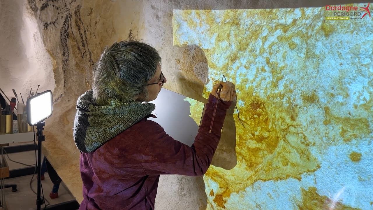 Une artiste peignant le fac-similé de la Salle des Taureaux aux Ateliers des Fac-Similés du Périgord